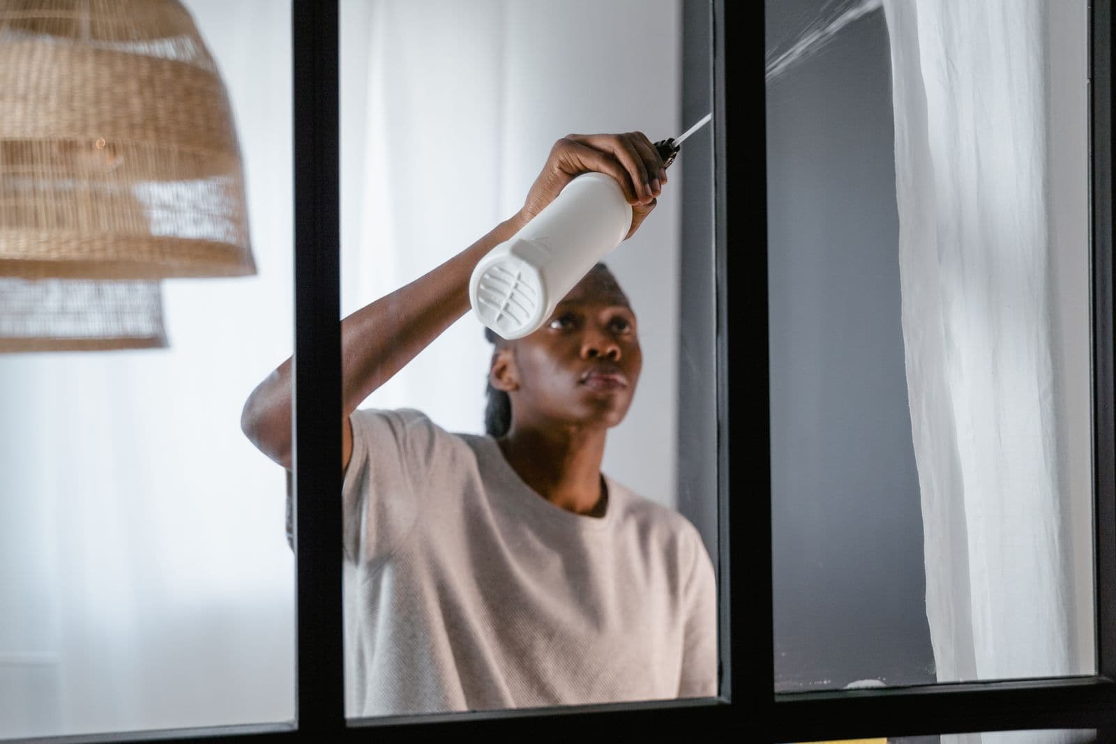 A cleaner wiping a window with a spray bottle